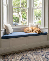 Dog sleeping on a navy boucle cushion on a bay window seat
