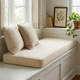 Cream corduroy cushion on a white window seat with knit pillows