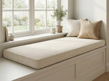 Cream corduroy cushion on a white window seat with two pillows