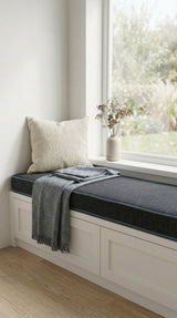 Charcoal piped cushion on a white window seat with a gray throw