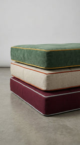 Stack of green, cream and burgundy cushions with contrast piping