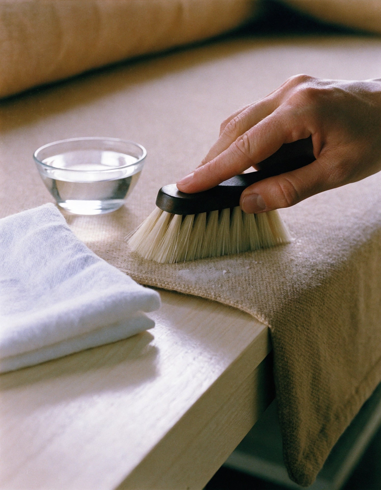 Brushing a woven cushion cover clean with a soft natural-bristle brush