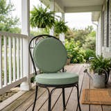 Sage green round seat and back cushions on an iron porch chair