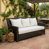 White cushions on a dark wicker patio sofa on a terracotta tile terrace