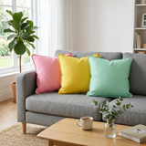 Pink dotted, yellow and mint throw pillows on a gray fabric sofa