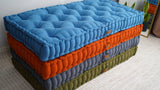 Angled close view of the blue tufted cushion on top of the stack