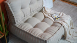 Angled view of the beige tufted floor chair seat and backrest