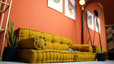 Mustard floor sofa against an orange wall with framed prints