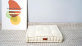 Cream tufted square floor cushion on a rug