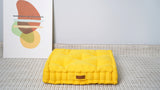 Yellow tufted square floor cushion on a rug