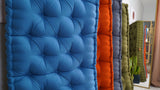 Close-up of the blue tufted surface beside the other upright cushions