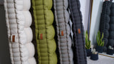 Close-up of upright tufted floor cushions in cream, olive, gray and charcoal