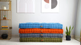 Stack of tufted linen floor cushions in blue, orange, gray and olive