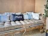 Gray tufted cushion with pillows on a rustic wooden daybed