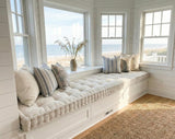 Cream tufted cushion on a white bay window seat facing the beach