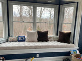 Cream tufted cushion on a window seat in a navy-walled room