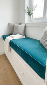 Teal velvet cushion on a white storage window seat