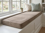 Light brown corduroy cushion on a window seat with two pillows