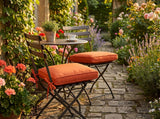 Orange cushions on two folding bistro chairs in a cottage garden