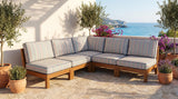 Gray striped outdoor cushions on a teak corner sofa on a sea-view terrace