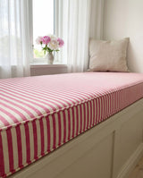 Close view of a pink and white striped window seat cushion