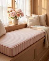 Pink striped cushion on a wooden window bench with peonies