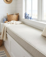 Beige pinstripe cushion on a long white window bench