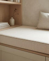 Close view of a beige pinstripe cushion on an oak bench