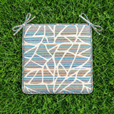 Top view of a square geometric tie-on cushion on grass