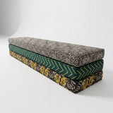 Stack of three long cushions in black geometric, green chevron and leaf prints