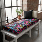 Bright graffiti print cushion on a white bench by a brick wall