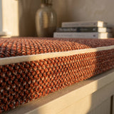 Close-up of a rust point weave cushion with cream piping