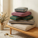 Stack of five point weave cushions with contrast piping on a bench