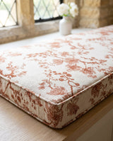 Close-up of a rust floral cushion corner with piping