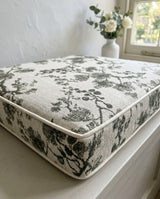 Close-up of a charcoal floral cushion with cream piping