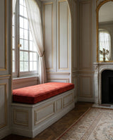 Red cushion on a white window seat in a paneled room