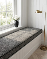 Charcoal textured cushion on a white window bench with a lamp