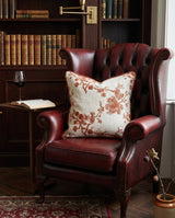 Rust blossom pillow on a burgundy leather wingback chair