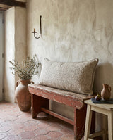 Oatmeal lumbar pillow on a rustic red bench