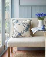 Blue blossom pillow with navy piping on a cream bench