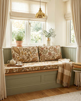 Gold paisley cushions on a sage bench under a brass pendant light
