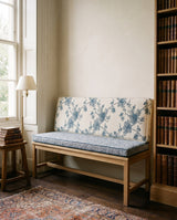 Blue floral and gray bench cushion set on a wooden bench beside bookshelves