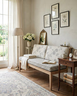 Pale blue floral cushion set on an oak bench below framed botanicals