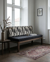 Charcoal seat cushion with two geometric back cushions on a wooden bench