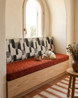 Rust seat cushion with a geometric backrest in an arched window alcove