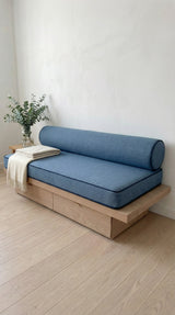 Blue linen daybed cushion and bolster on a light oak base