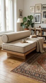 Cream daybed cushion and bolster on an oak platform with a red rug