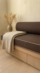 Close view of a brown daybed cushion with piping and a bolster