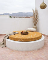 Round mustard cushion on a round white terrace seat