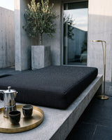 Charcoal cushion on a concrete bench on a modern patio